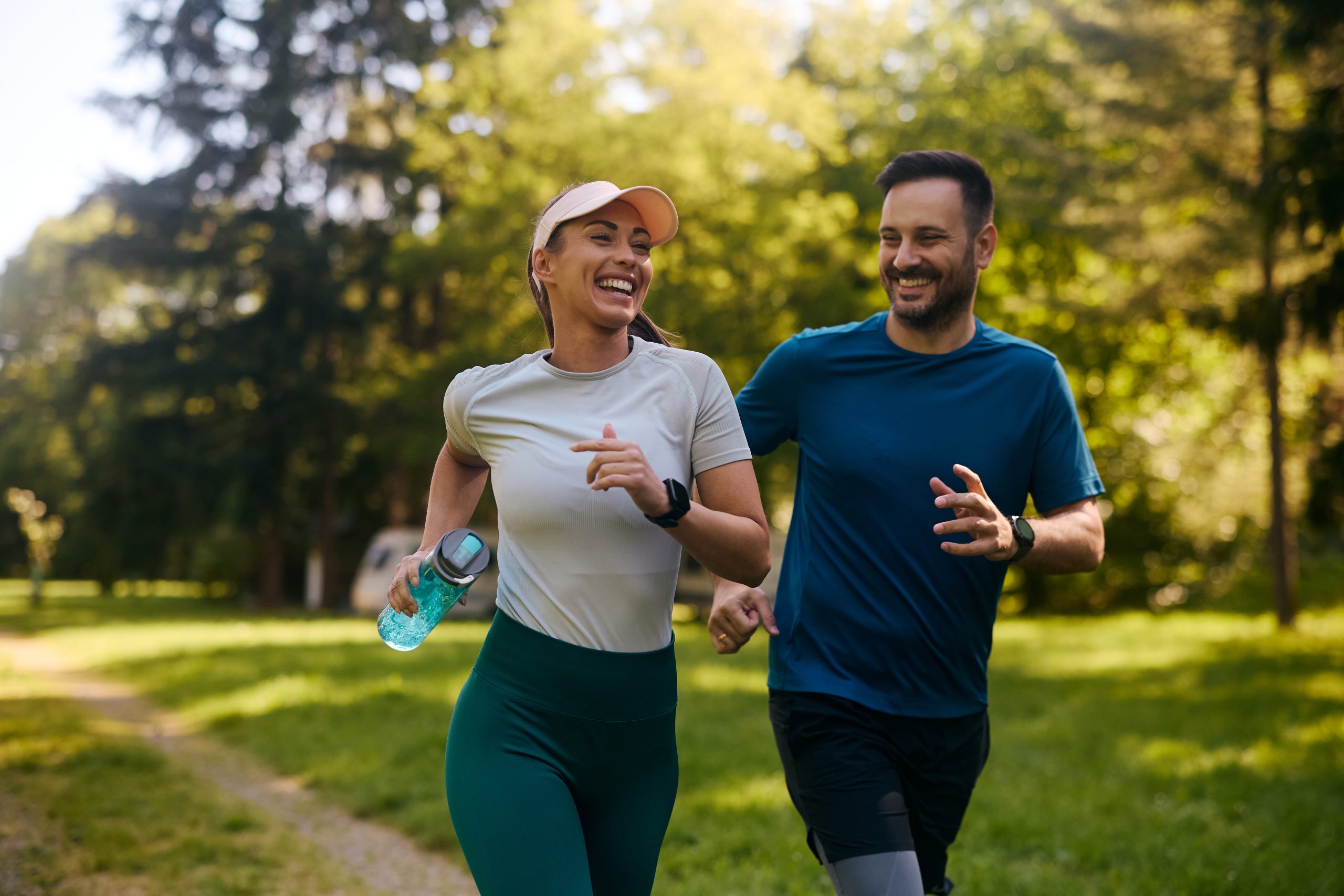 Man and woman jogging together outdoors in a park.