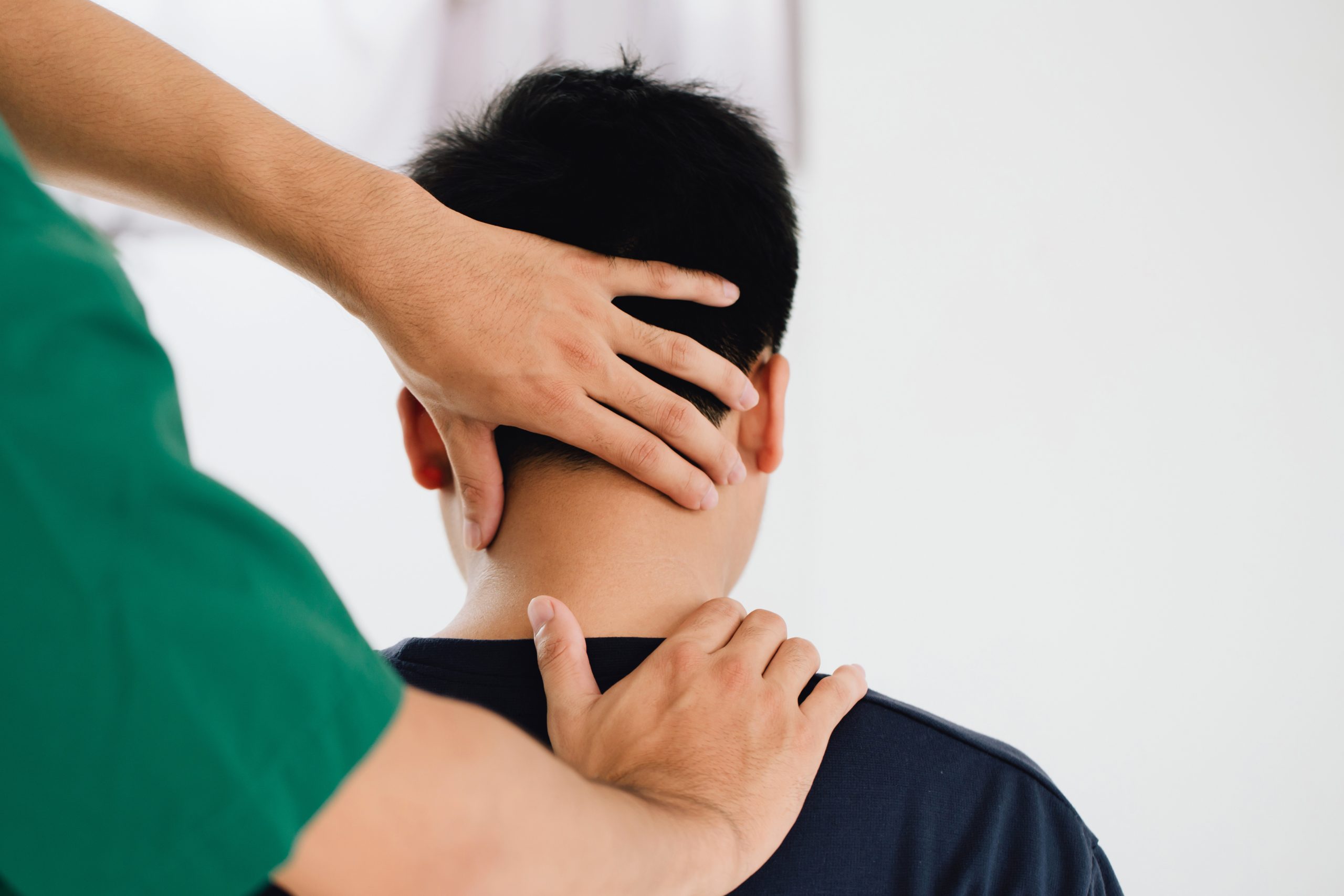 Chiropractor assessing a patient’s neck and upper spine.