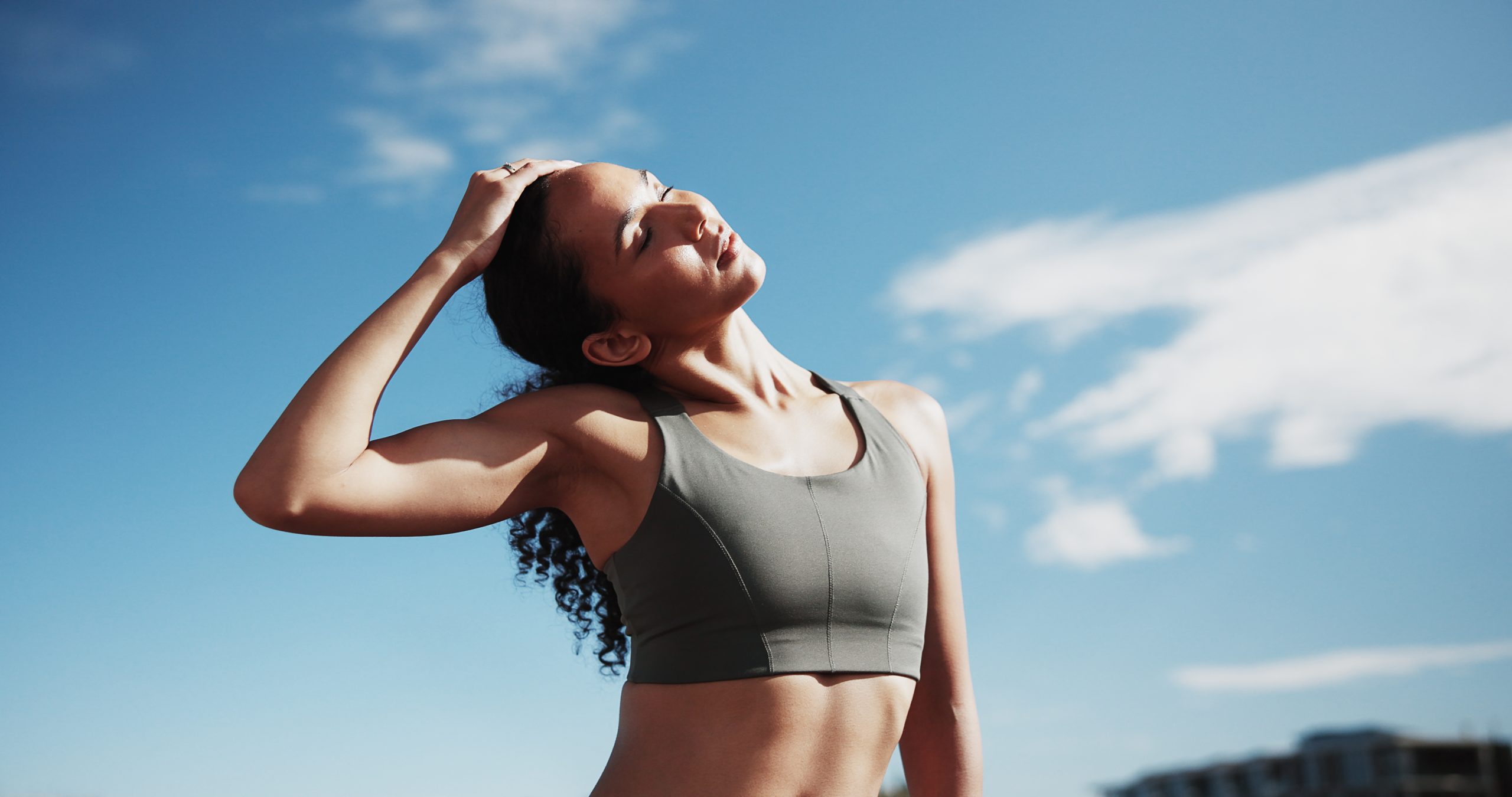 Woman stretching her neck outdoors before or after exercise.