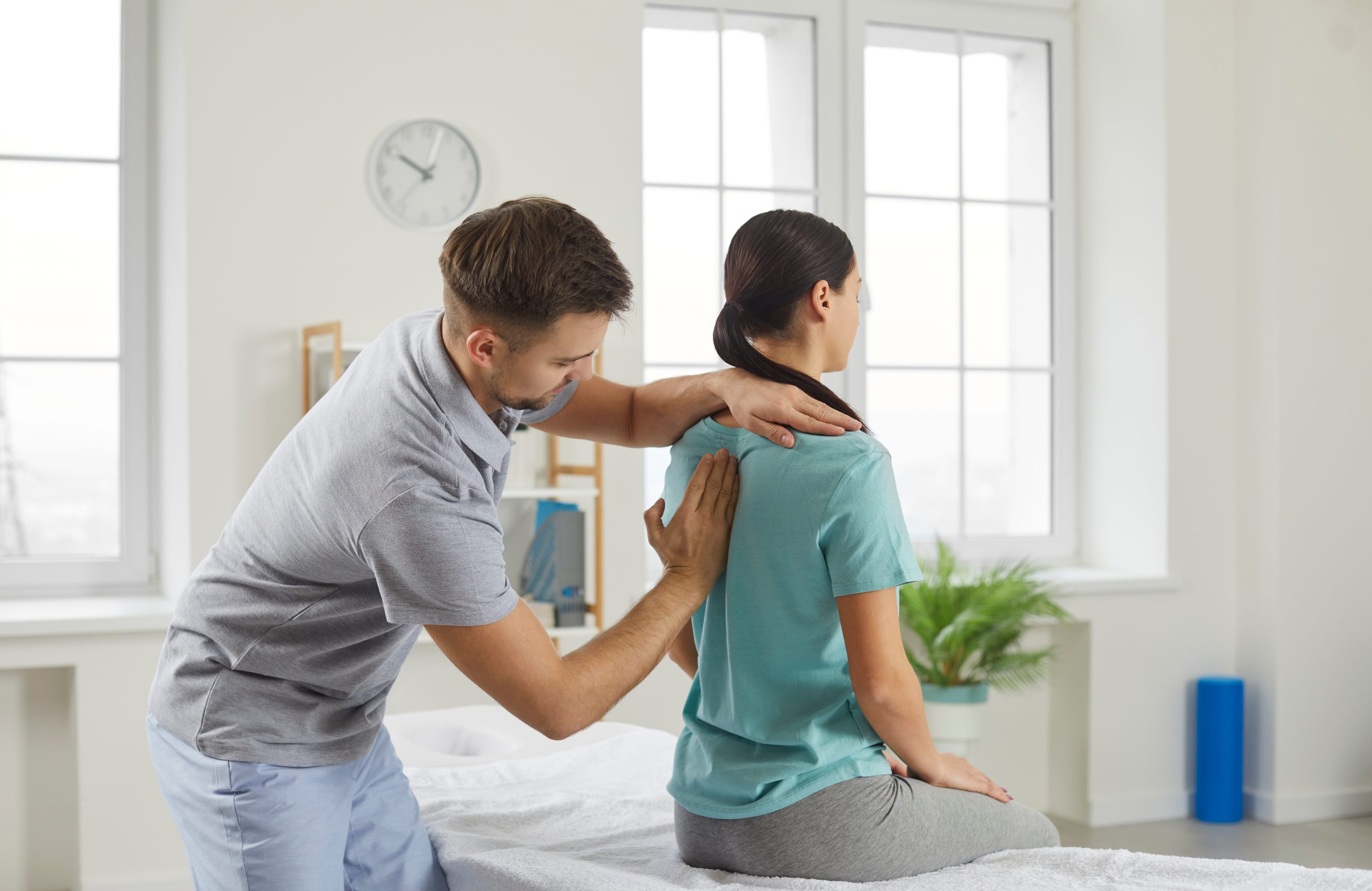 Chiropractor assessing a patient’s upper back and shoulder alignment.