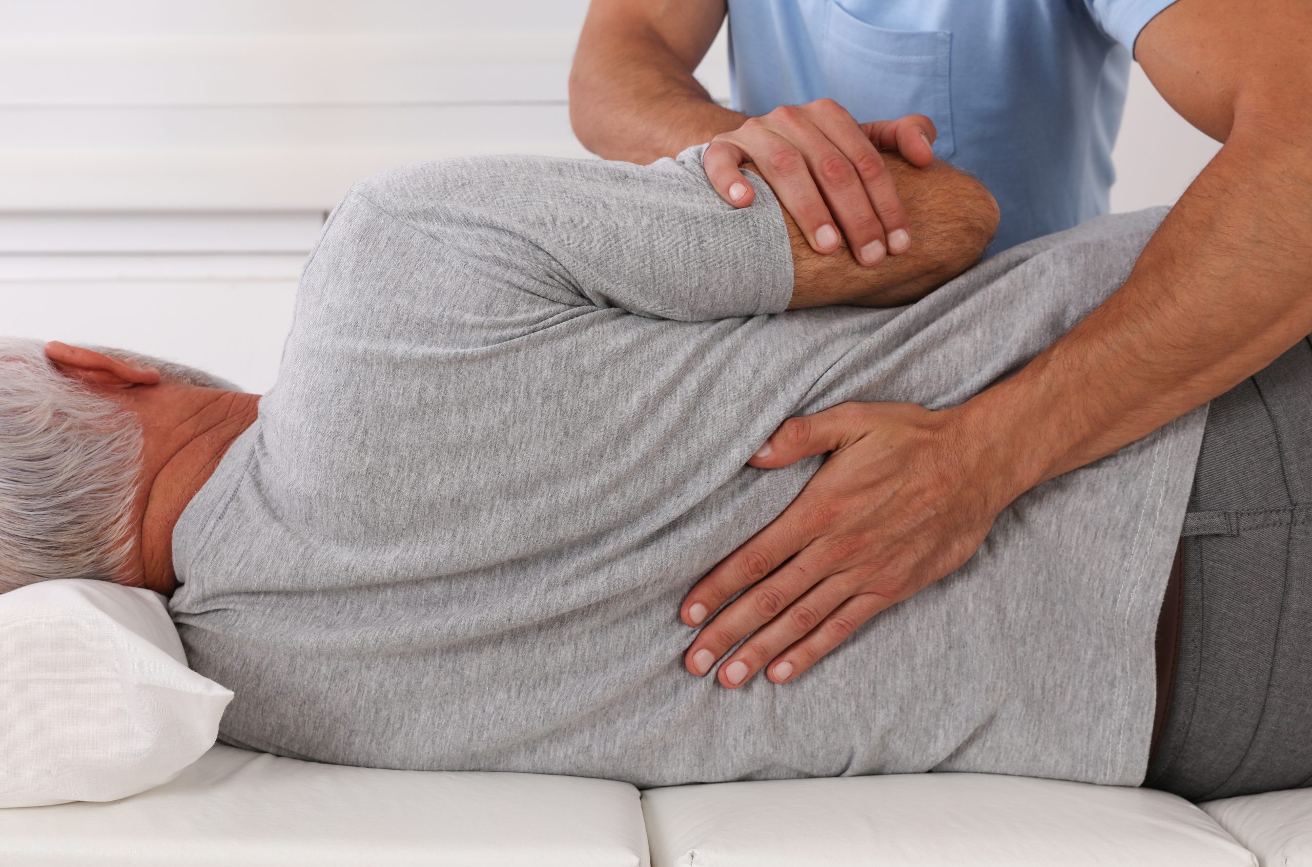 Chiropractor performing a side-lying adjustment on an older patient.