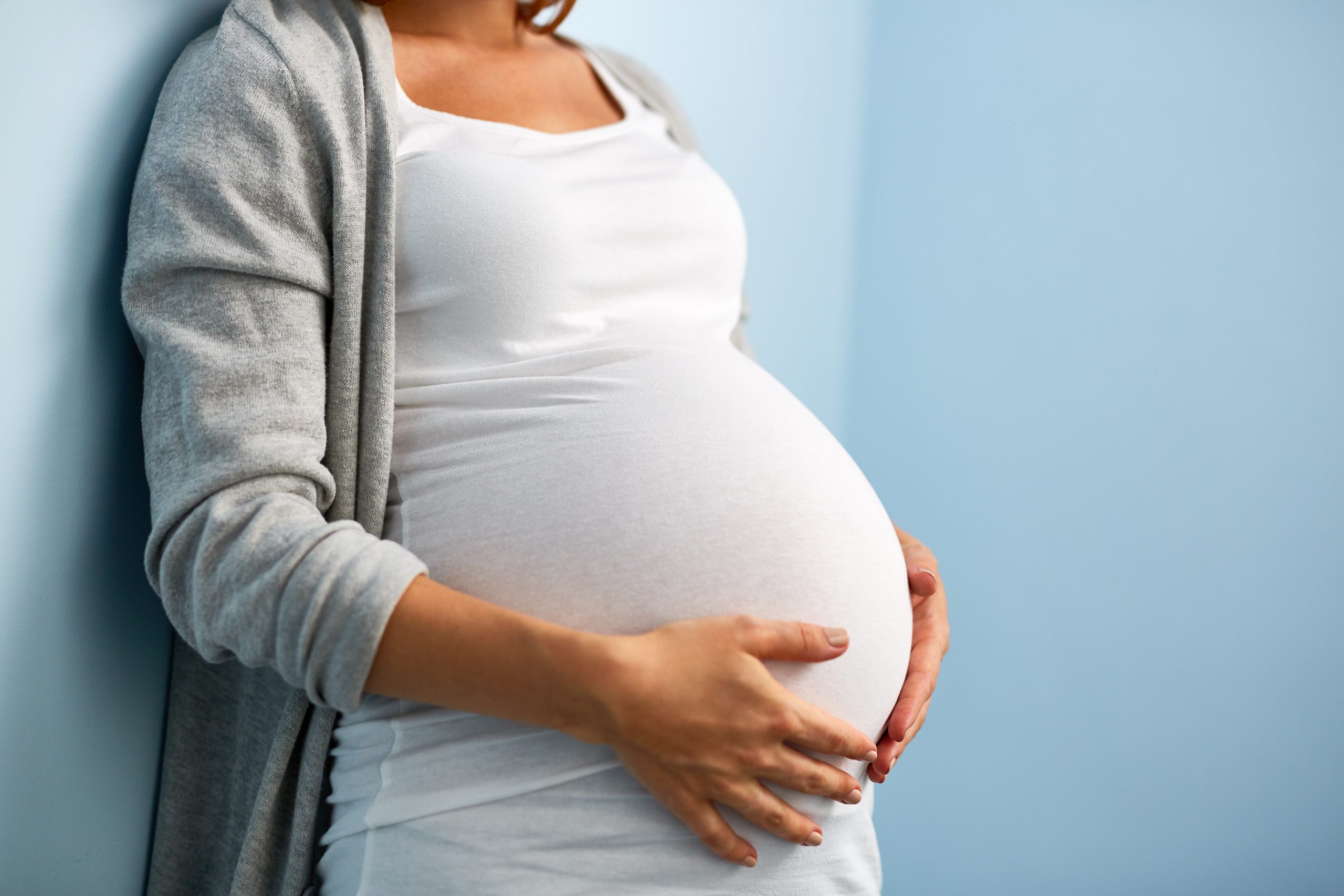 Pregnant woman gently holding her belly during pregnancy.